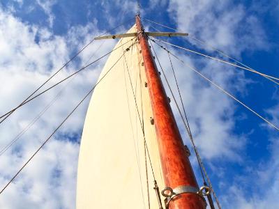 Schooner mast and sail in blue sky